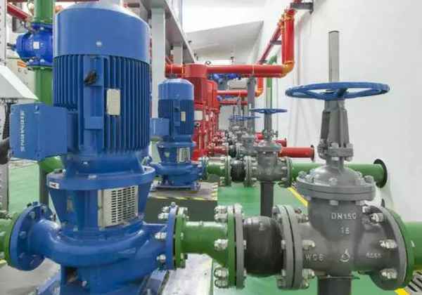 Industrial mechanical room with blue pumps, red and green pipes, and metal valves, clean and organized layout